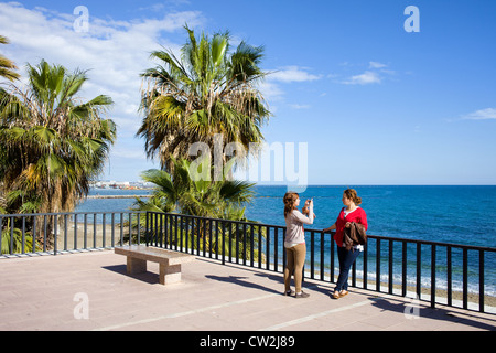 Deux femmes prenant des photos de la mémoire sur la promenade, dans la ville de villégiature de Marbella sur la Costa del Sol en Espagne, le sud de l'Andalousie. Banque D'Images