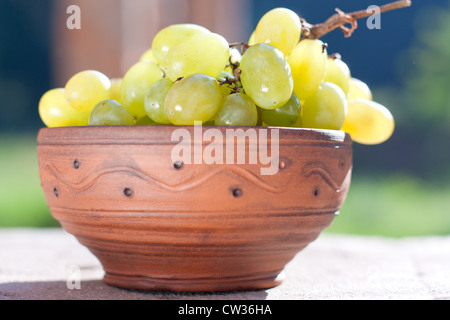 Grappe de raisins dans un bol en céramique, extérieur Banque D'Images