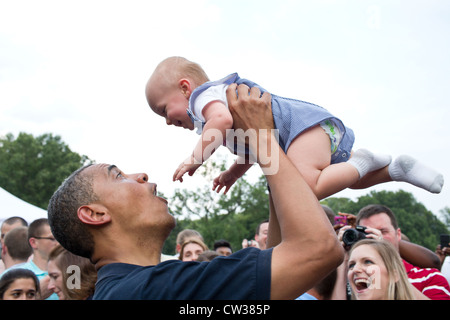 Le président Barack Obama est titulaire d'un bébé pendant que vous souhaits au cours d'une célébration de la fête de l'indépendance sur la pelouse Sud de la Maison Blanche le 4 juillet 2012 à Washington, DC. Banque D'Images