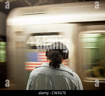 Un auditeur de musique porte ses Beats by Dr. Dre sur l'oreille casque sur une plate-forme du métro à New York Banque D'Images