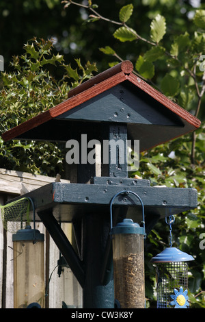 Table de jardin avec des oiseaux dans les mangeoires de graines pendaison Banque D'Images