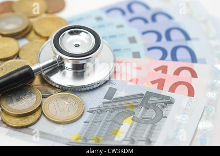 Un stéthoscope médical placé sur les pièces et billets de l'euro. Banque D'Images