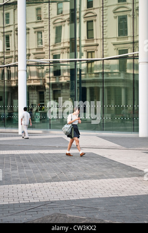 Jeune femme marche en face de l'Imperial College, Exhibition Road, South Kensington, London, UK Banque D'Images