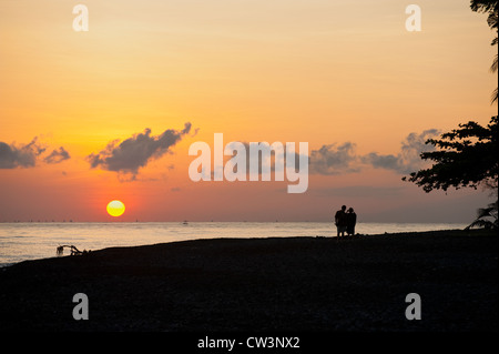 Un couple se promener le long d'une plage de Bali tropical au cours d'un magnifique lever de soleil dans le village de Jemeluk, Amed. Banque D'Images