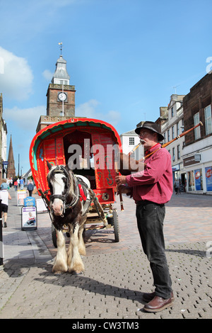 Tuyaux homme jouant en face de style Gypsy Caravan à chevaux à Dumfries, Écosse, Royaume-Uni Banque D'Images