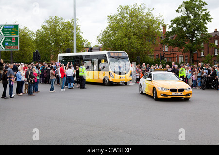 Foules bordent les rues de Birmingham, West Midlands pour attendre le passage de la flamme olympique et son porteur précédé de sponsors Banque D'Images