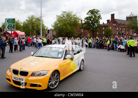 Foules bordent les rues de Birmingham, West Midlands pour attendre le passage de la flamme olympique et son porteur précédé de sponsors Banque D'Images