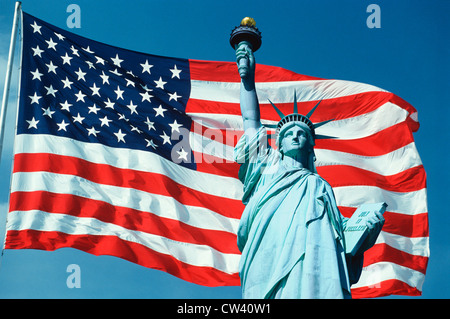Cet un drapeau américain sur mât en agitant au vent contre le ciel bleu. Moitié supérieure Statue Liberty composée numériquement sur la droite Banque D'Images