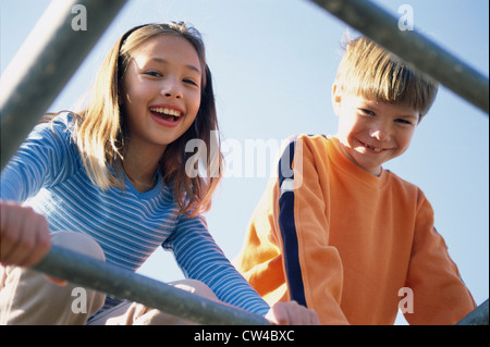 Portrait d'une fille et un garçon sur monkey bars Banque D'Images