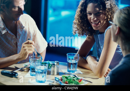 Deux jeunes femmes et un jeune homme assis dans un restaurant. Banque D'Images