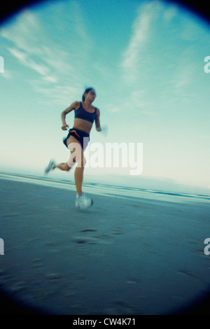 Low angle view of a young woman running on the beach Banque D'Images
