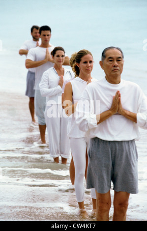 Groupe de personnes faisant du yoga sur la plage Banque D'Images