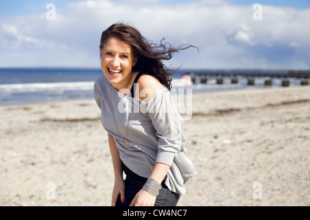 Young adult woman smiling et à heureux sur la plage contre le ciel clair Banque D'Images