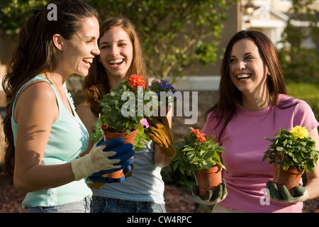 Maman avec ses filles gaies holding potted plants Banque D'Images