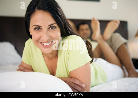 Portrait of a young woman lying in the bed with a young man reclining derrière elle Banque D'Images