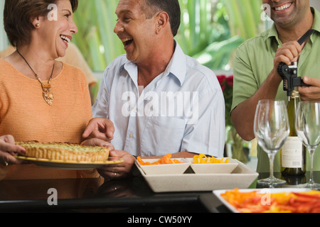 Close-up of a young couple avec un homme mûr de dévisser le bouchon d'une bouteille de vin Banque D'Images