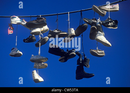 Plusieurs paires de chaussures jetées sur le fil électrique par lacets Banque D'Images