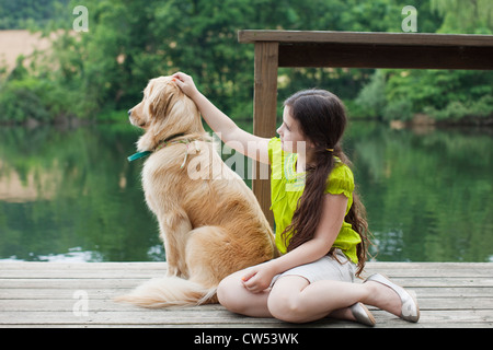 Girl with Golden Retriever on jetty Banque D'Images