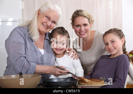 Mère, grand-mère, et les filles la cuisson des crêpes Banque D'Images