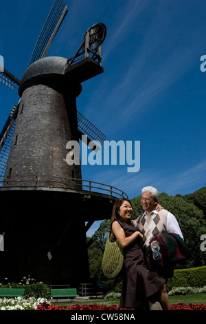 Mature couple standing in front of traditional windmill in park et souriant le Golden Gate Park San Francisco California USA Banque D'Images