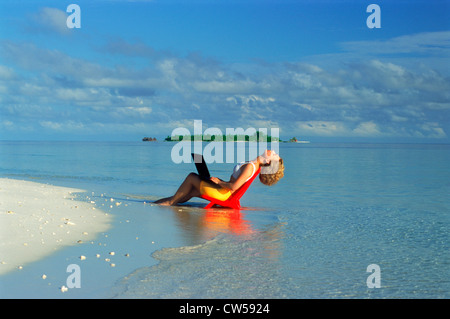 Femme sur chaise de plage de détente avec tête en arrière et les yeux fermés holding laptop computer pendant les vacances d'été à Paradise Banque D'Images