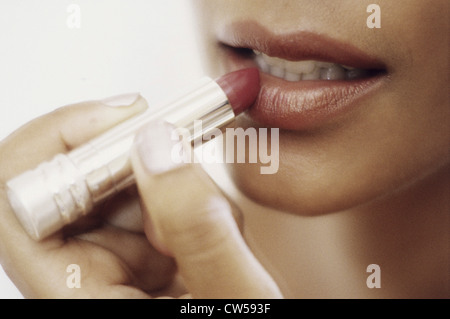 Young woman applying lipstick Banque D'Images