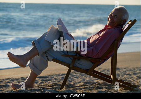 Hauts homme assis sur une chaise et tenant un journal Banque D'Images