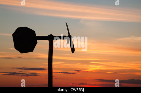 Petit moulin girouette style silhouette au-dessus de ciel coucher de soleil orange Banque D'Images