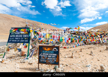 Deux panneaux ornés de drapeaux de prière publicité Tsomoriri Super Deluxe tentes au Col Namshangla au Ladakh, Inde Banque D'Images