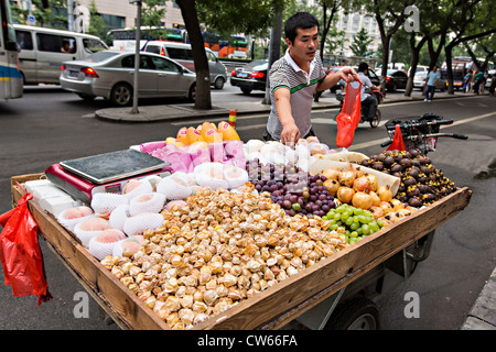 Un vendeur de fruits le long d'une route très fréquentée à Beijing, Chine Banque D'Images