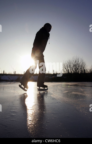 Village resplendissant femme tout en patinant sur un lac gelé Banque D'Images