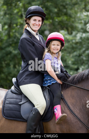 Une jeune femme et de la jeune fille s'assit sur un cheval à l'extérieur sur une journée ensoleillée Banque D'Images