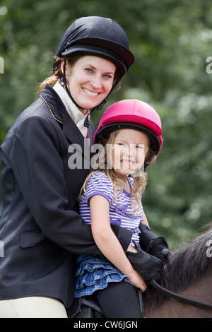 Une jeune femme et de la jeune fille s'assit sur un cheval à l'extérieur sur une journée ensoleillée Banque D'Images