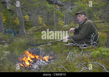 Le wapiti, l'orignal (Alces alces alces), hunter faire le café sur un feu de camp au cours d'une pause, la Norvège, Nord-Trondelag, Flatanger Banque D'Images