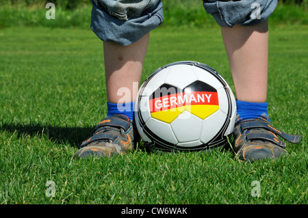 Garçon debout sur une pelouse avec un ballon entre les pieds avec l'écriture 'Allemagne', l'Allemagne, Bade-Wurtemberg Banque D'Images