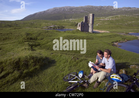 Couple après bikeride aux côtés d'Ardvreck Castle, Loch Assynt, Royaume-Uni, Ecosse, Sutherland Banque D'Images