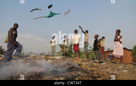 Les enfants avec des cerfs-volants sur une décharge publique à des bidonvilles tandis que la fumée s'élève de la combustion des déchets, BURUNDI, Bujumbura mairie, Buyenzi, Bujumbura Banque D'Images