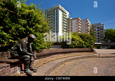 Sculpture d'un homme assis en face de maisons de la ville, de l'Allemagne, en Rhénanie du Nord-Westphalie, Ruhr, Kamp-Lintfort Banque D'Images