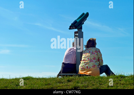 Deux personnes assis à côté coin télescope sur digue, ALLEMAGNE, Basse-Saxe, Neuharlingersiel Banque D'Images