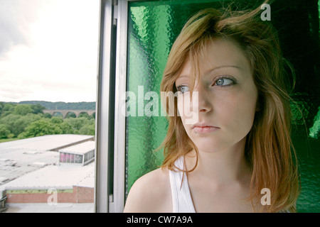 Jeune femme rousse mélancolique à la fenêtre ouverte, hors de l'Allemagne Banque D'Images