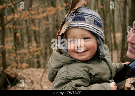 Little Boy holding sur mère en forêt d'automne, Allemagne Banque D'Images