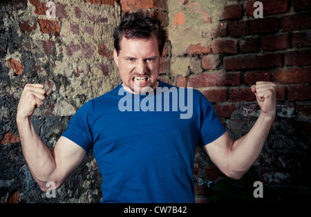 Strong, jeune homme devant y brick wall Banque D'Images