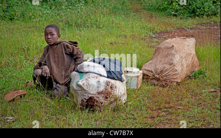 Petit garçon assis à côté d'une route, certains biens avant un voyage à la capitale, Burundi, Ngozi, Ngozi Banque D'Images