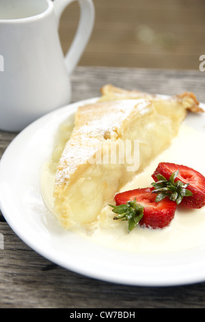 Tarte aux pommes avec de la crème fraîche et garni de tranches de fraises Banque D'Images