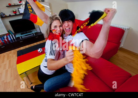 Deux terrains de soccer fans célébrer dans la salle de séjour, Allemagne Banque D'Images