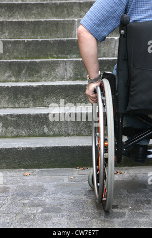 Homme d'attente dans un fauteuil en face d'un escalier Banque D'Images