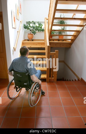 Femme dans un fauteuil roulant en face de l'escalier en bois Banque D'Images