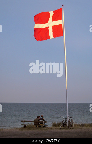 Deux personnes assises sur un banc près du drapeau national danois à la plage, au Danemark, Bornholm, Soemarken Banque D'Images