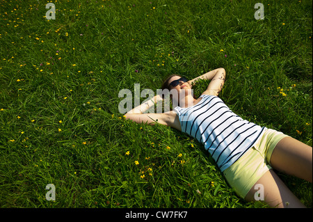 Teenage girl with sunglasses couchée dans un pré relaxing Banque D'Images
