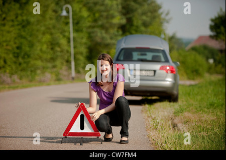 Jeune fille ayant une panne sur une route de campagne est mise en place d'un triangle d'avertissement Banque D'Images